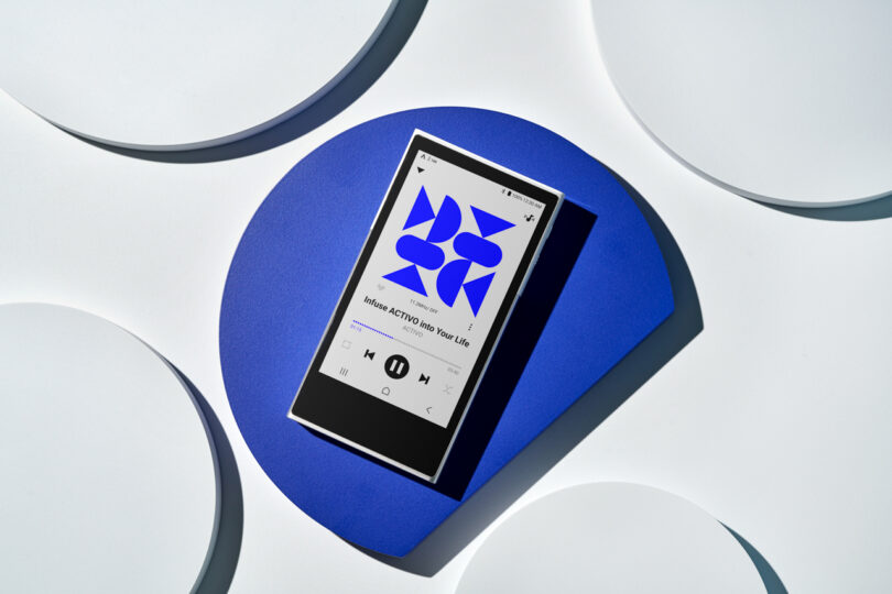 A smartphone with a music player interface displayed on the screen, placed on a blue, circular stand, resembles the sleek design of the Astell&Kern P1.